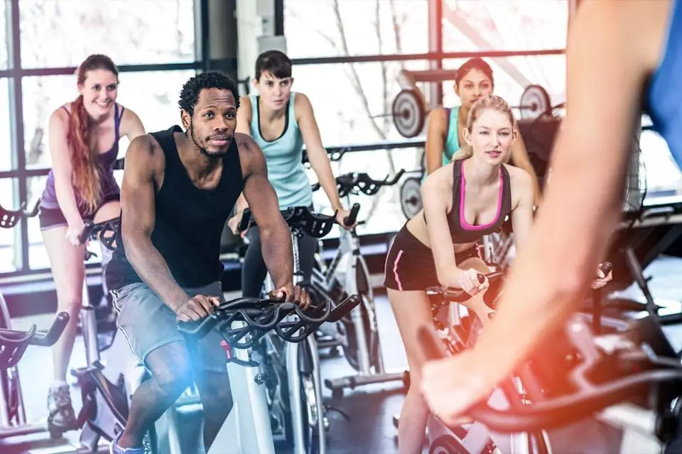 multiracial group of 20 or 30-somethings on bikes in an indoor cycling class