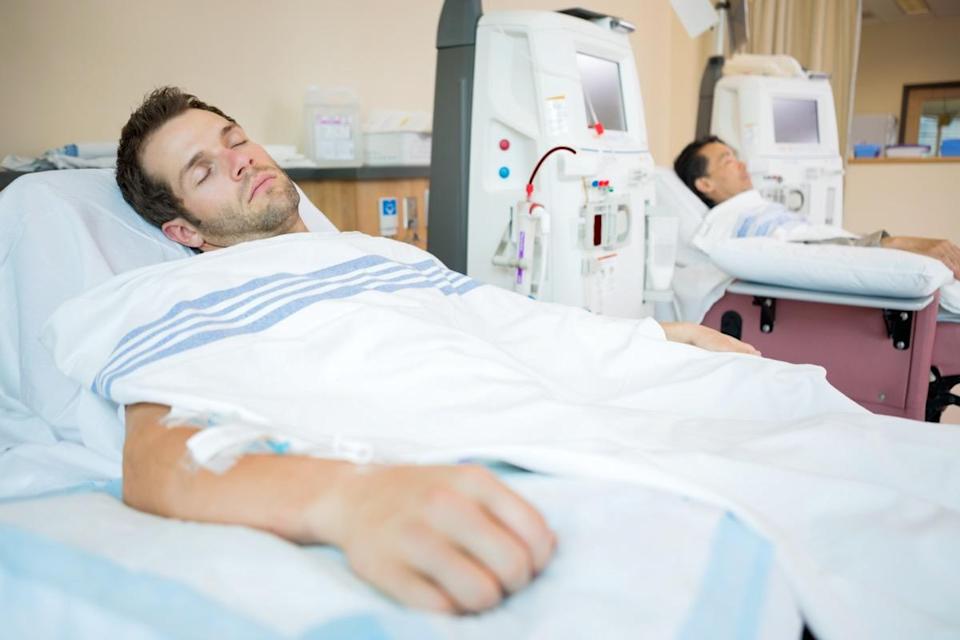 Male patients sleeping while receiving renal dialysis in chemo room at hospital