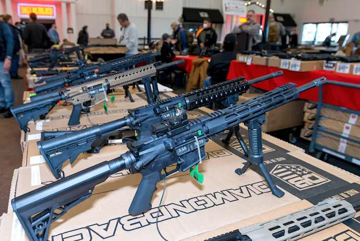 Rifles on display on a table at a gun show.