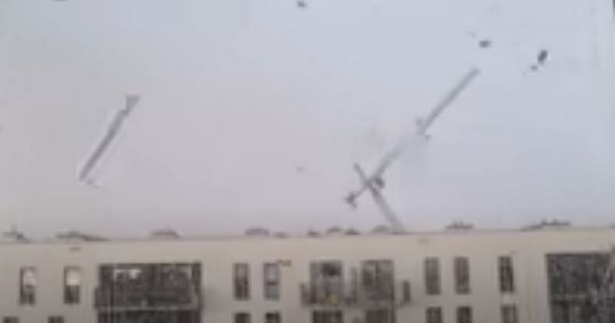 Horrifying moment 98ft crane is blown over killing two workers as storm rages on